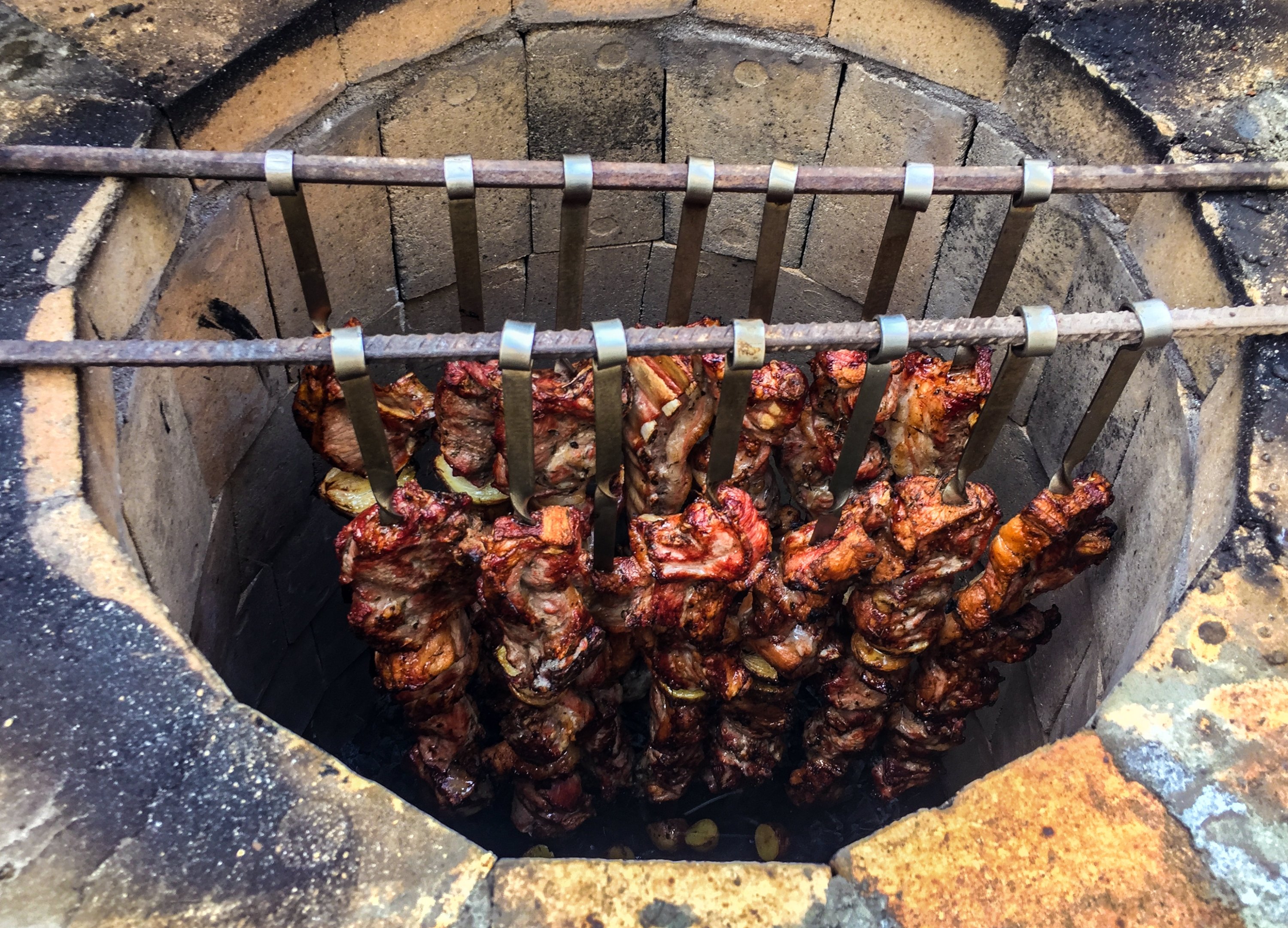 Tandır kebab skewers are left suspended in a tandoor to cook slowly. (Shutterstock Photo)