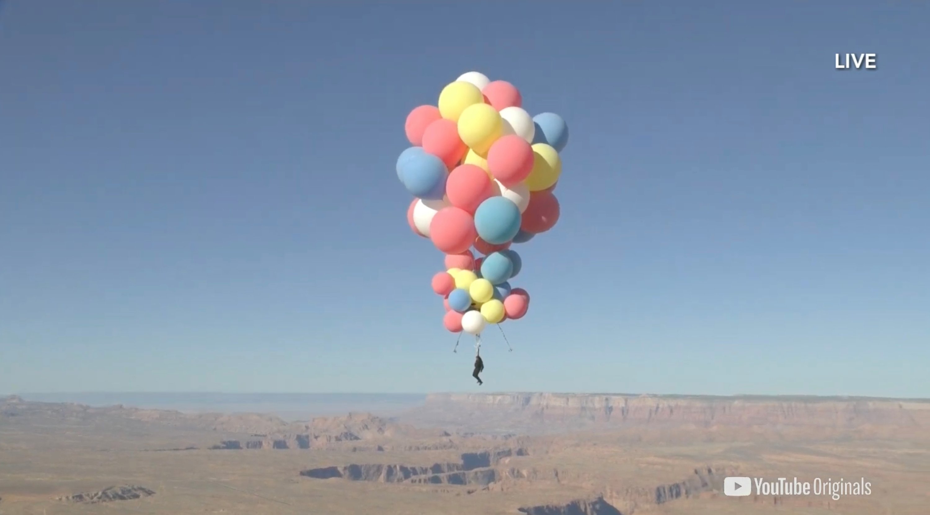 Extreme performer David Blaine hangs with a parachute under a cluster of balloons during a stunt to fly thousands of feet into the air, in a still image from video taken over Page, Arizona, U.S., Sept. 2, 2020. (David Blaine handout via Reuters)