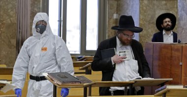 In this file photo, an Israeli police officer, dressed in a protective outfit, enters a yeshiva (a Jewish educational institution for studies of traditional religious texts) in the Israeli city of Bnei Brak during a check to ensure that social distancing measures imposed by Israeli authorities meant to curb the spread of the coronavirus are being followed, April 2, 2020. (AFP Photo)