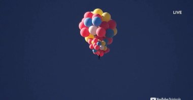 Extreme performer David Blaine hangs with a parachute under a cluster of balloons during a stunt to fly thousands of feet into the air, in a still image from video taken over Page, Arizona, U.S., Sept. 2, 2020. (David Blaine handout via Reuters)