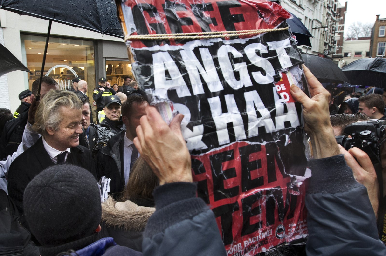 A man holds a placard reading "Don't Give Hate And Fear A Vote" as firebrand anti-Islam lawmaker Geert Wilders (L) passes by during a campaign stop in Breda, Netherlands, March 8, 2017. (AP Photo)