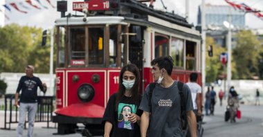 A woman wearing a protective mask and a man with a mask below his chin walk on a street in Istanbul, Turkey, Sept. 5, 2020. (DHA Photo)