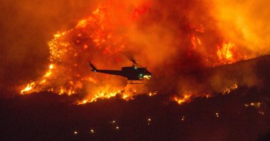 A helicopter prepares to drop water on a wildfire in Yucaipa, California, U.S., Sept. 5, 2020. (AP Photo)