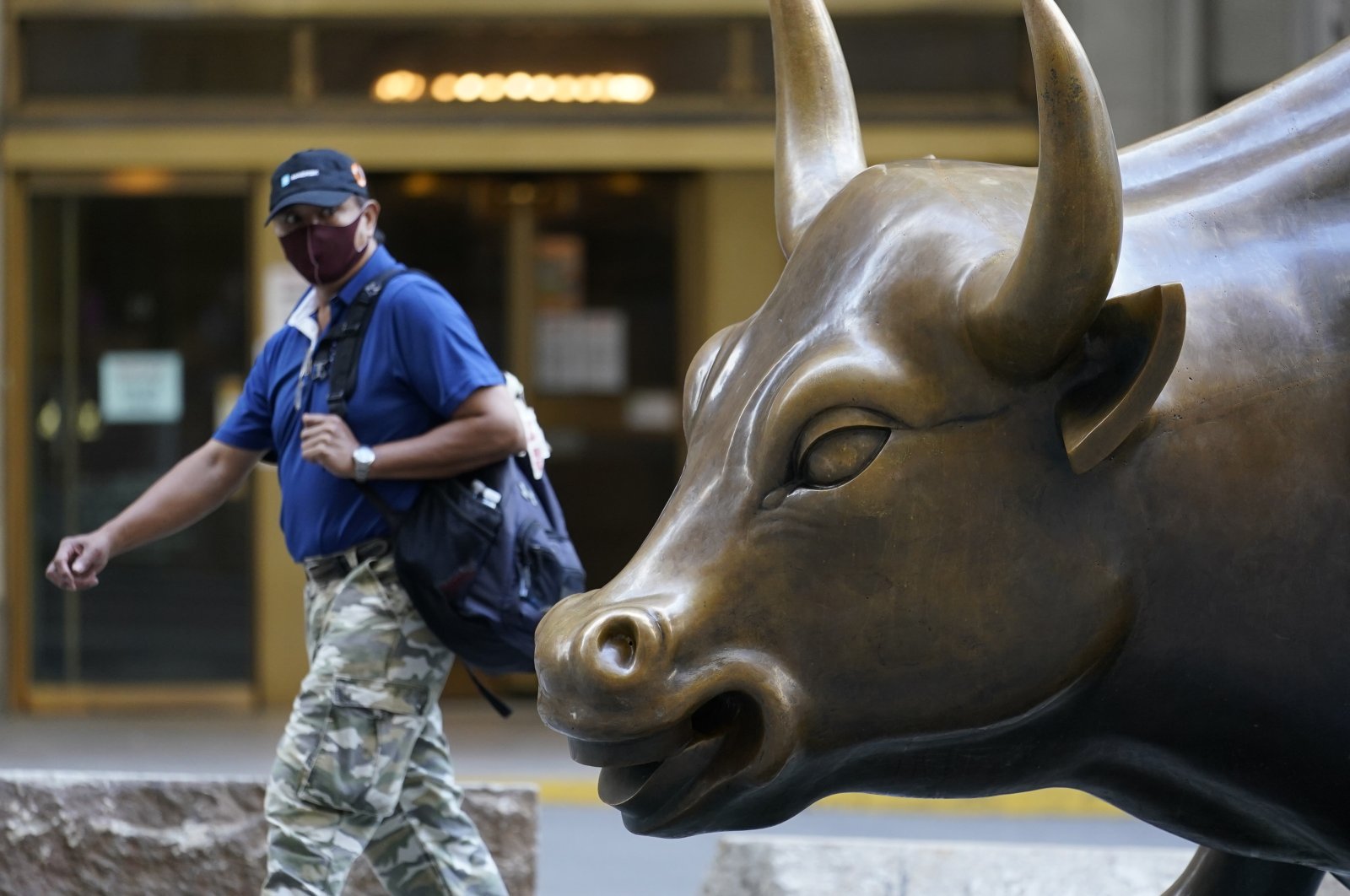 A man wearing a mask passes the Charging Bull statue in New York's financial district, Sept. 8, 2020. (AP Photo)
