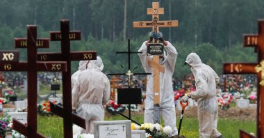 Grave diggers wearing personal protective equipment (PPE) bury a person, who presumably died of the coronavirus disease (COVID-19) in the special purpose section of a graveyard on the outskirts of Saint Petersburg, Russia on June 10, 2020. (Reuters Photo)