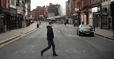 A man wearing a face mask due to the COVID-19 pandemic crosses an almost empty road in the center of Bolton, northern England, Sept. 9, 2020. (AFP Photo)