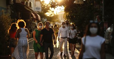 Tourists wearing protective masks walk on a street, in Ayvalık, a town in Balıkesir, western Turkey, Sept. 9, 2020. (AP Photo)