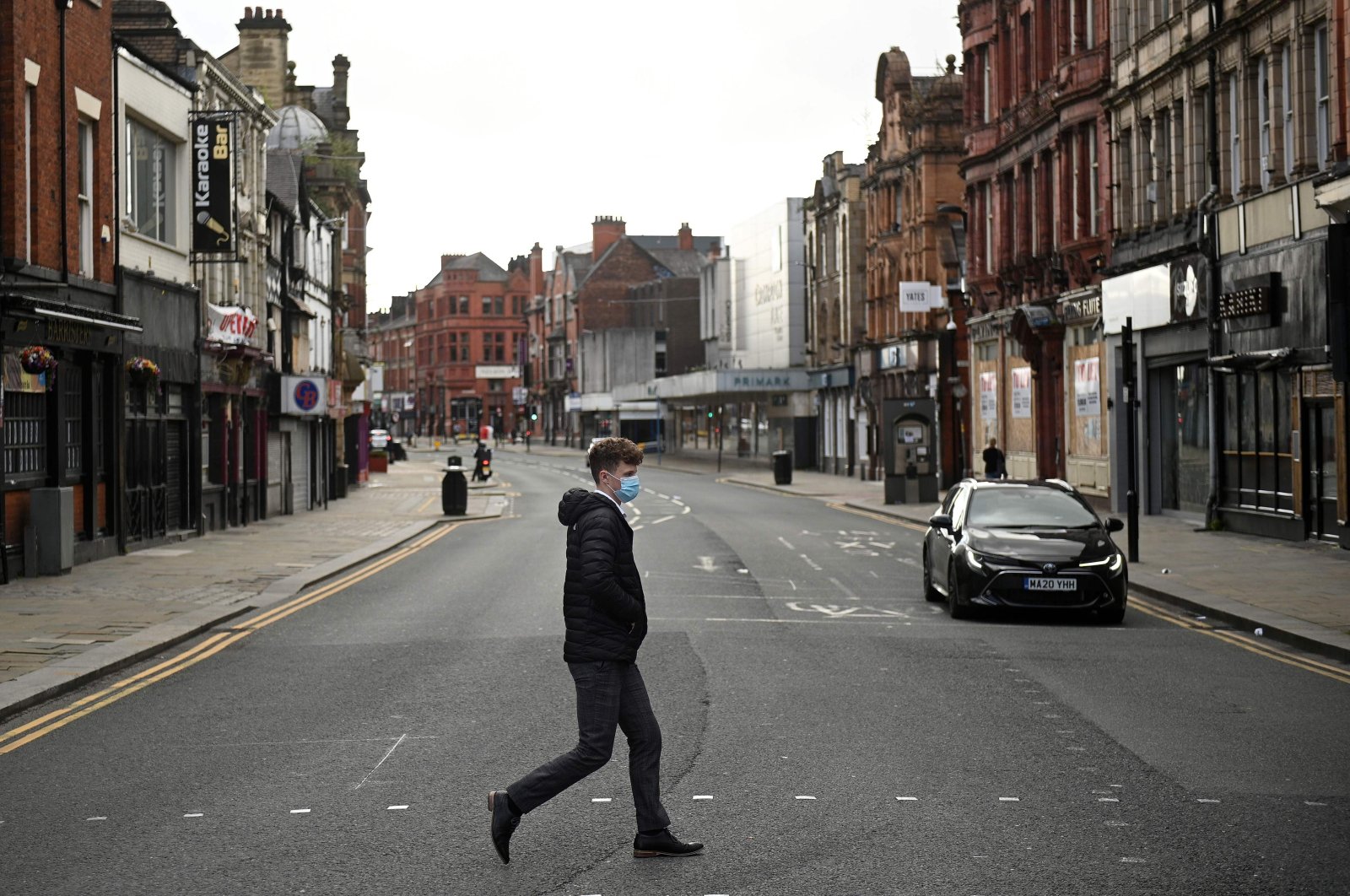 A man wearing a face mask due to the COVID-19 pandemic crosses an almost empty road in the center of Bolton, northern England, Sept. 9, 2020. (AFP Photo)