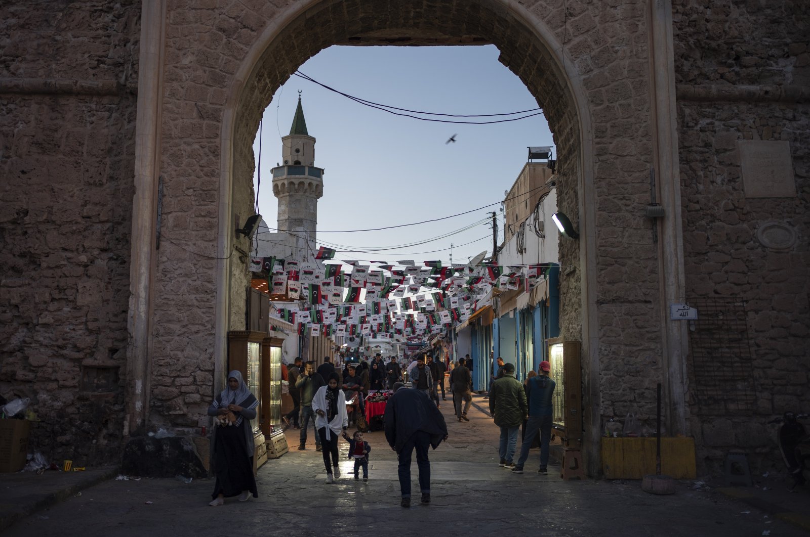 People walk near one of the entrances of the Old City in Tripoli, Libya, Feb. 25, 2020. (AP Photo)