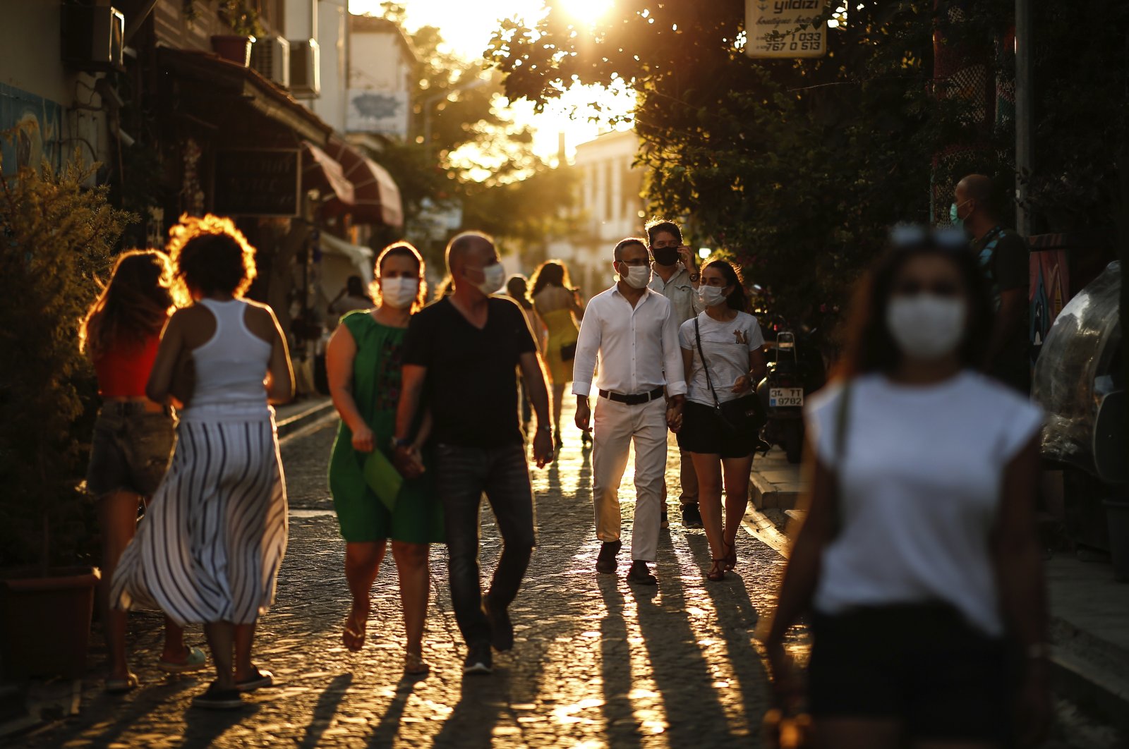 Tourists wearing protective masks walk on a street, in Ayvalık, a town in Balıkesir, western Turkey, Sept. 9, 2020. (AP Photo)