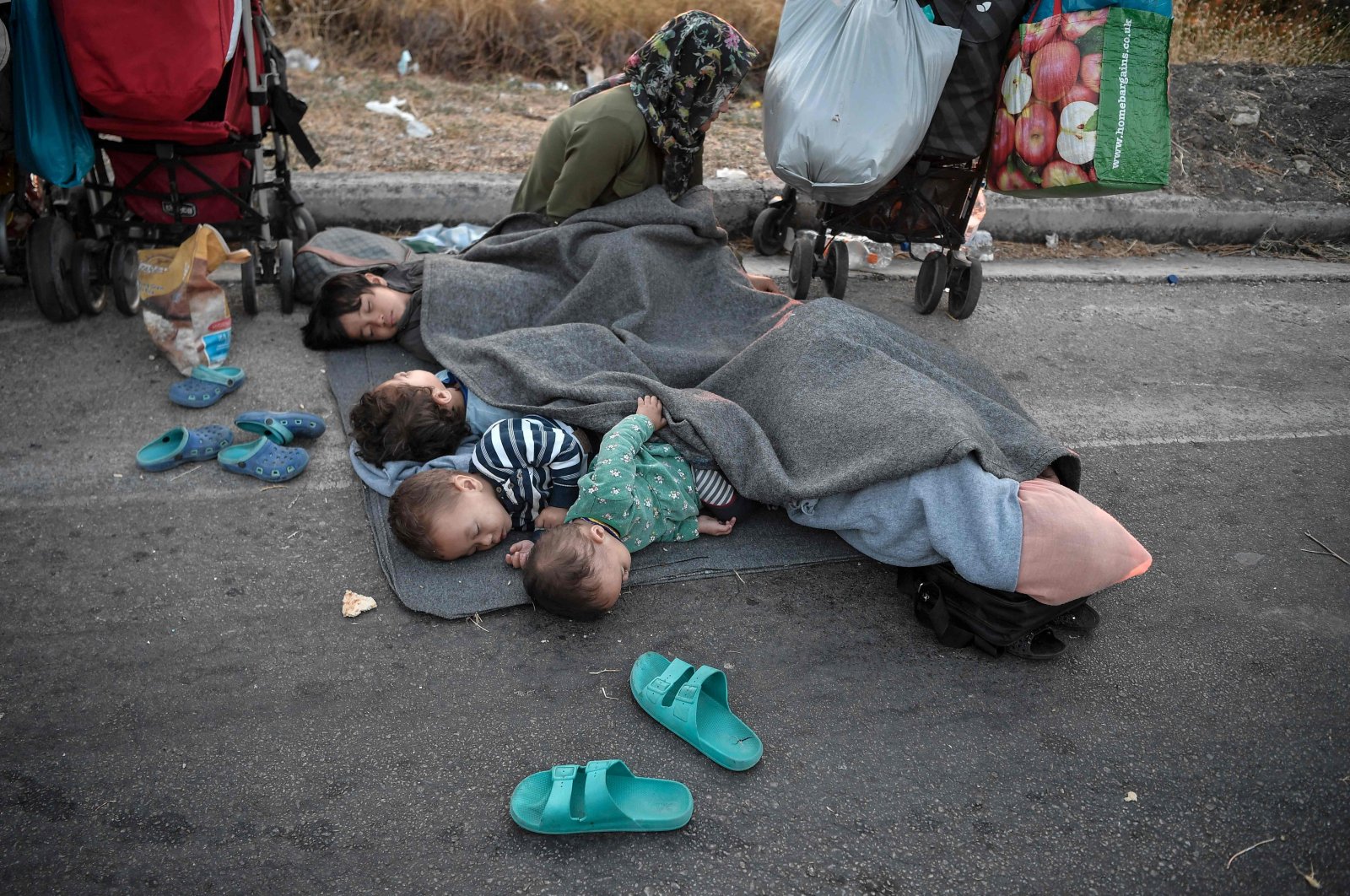 Migrants rest as they spend the night on the road near Mytilene, after a fire destroyed Greece's largest refugee camp, Moria, on the island of Lesbos, early on Sept. 10, 2020. (AFP Photo)