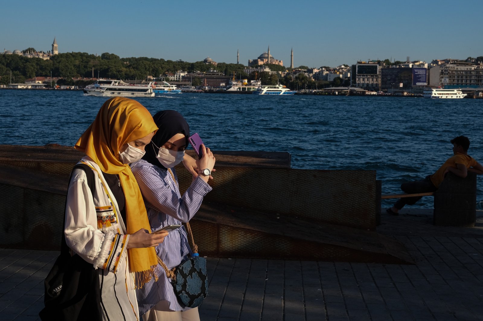 Women wearing face masks check their phones as they walk in Istanbul, Turkey, Aug. 12, 2020. (EPA Photo)