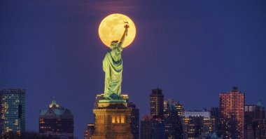 The full moon rises behind the Statue of Liberty in New York, March 9, 2020. (AP Photo)