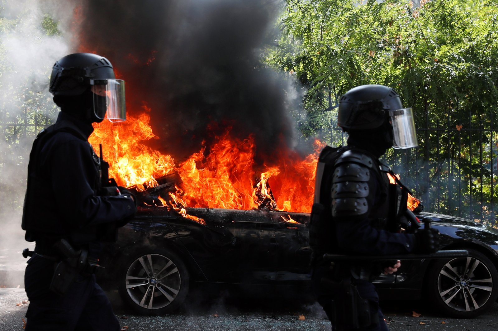 French CRS riot police officers walk past a burning car during a demonstration of the yellow vests movement in Paris, France Sept. 12, 2020. (Reuters Photo)