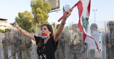 An anti-government protester carries a national flag as she shouts slogans in front of Lebanese army soldiers, Baabda, east Beirut, Sept. 12, 2020. (EPA Photo)