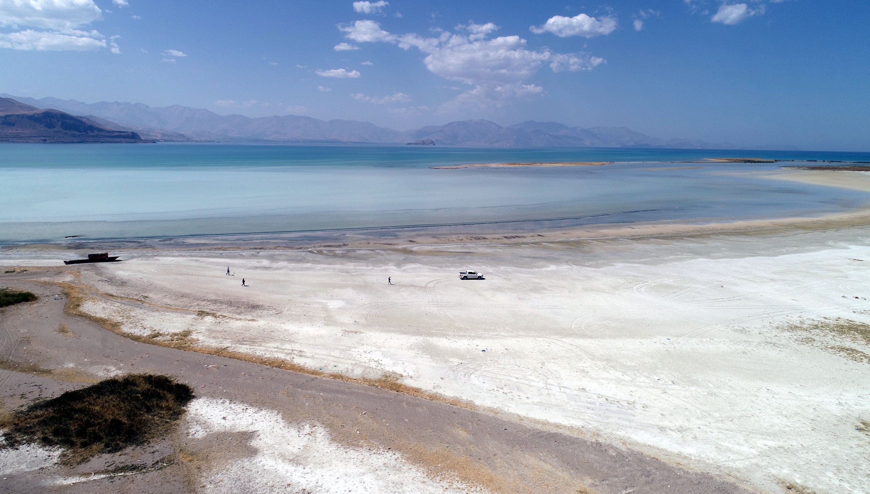 People walk near a boat that ran aground after water levels in Lake Van retreated by record amounts, Van province, eastern Turkey, Sept. 15, 2020. (DHA Photo)