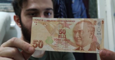 Doğan Kaya displays the misprinted TL 50 bill, with the defect visible on top right, in Bursa, Turkey, Sept. 15, 2020. (DHA Photo)