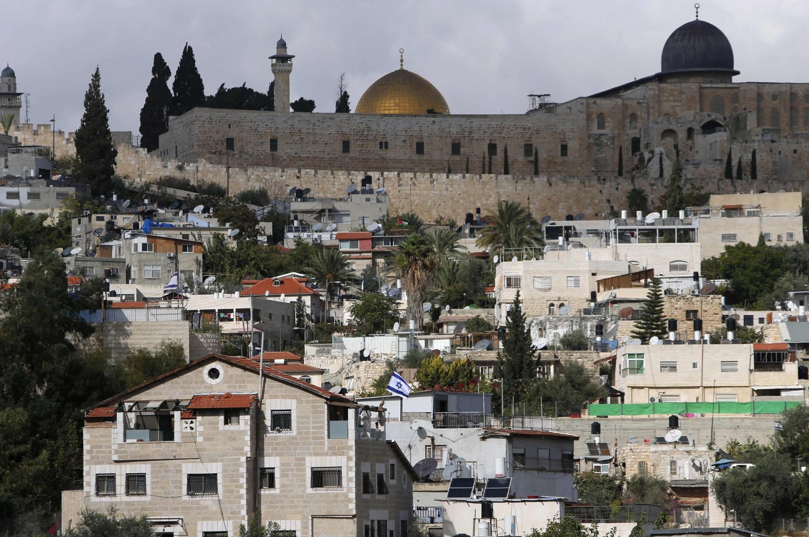 The Dome of the Rock and Al-Aqsa Mosque are seen in background as an Israeli flag flutters from atop a home of Jewish settlers in Silwan, a mostly Palestinian district abutting the Old City, Nov. 3, 2014. (Reuters Photo)
