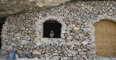 A woman gazes out of the window of a home built in a cave in the village of Farasin, west of Jenin, in the northern occupied West Bank, Aug. 4, 2020. (AFP Photo)