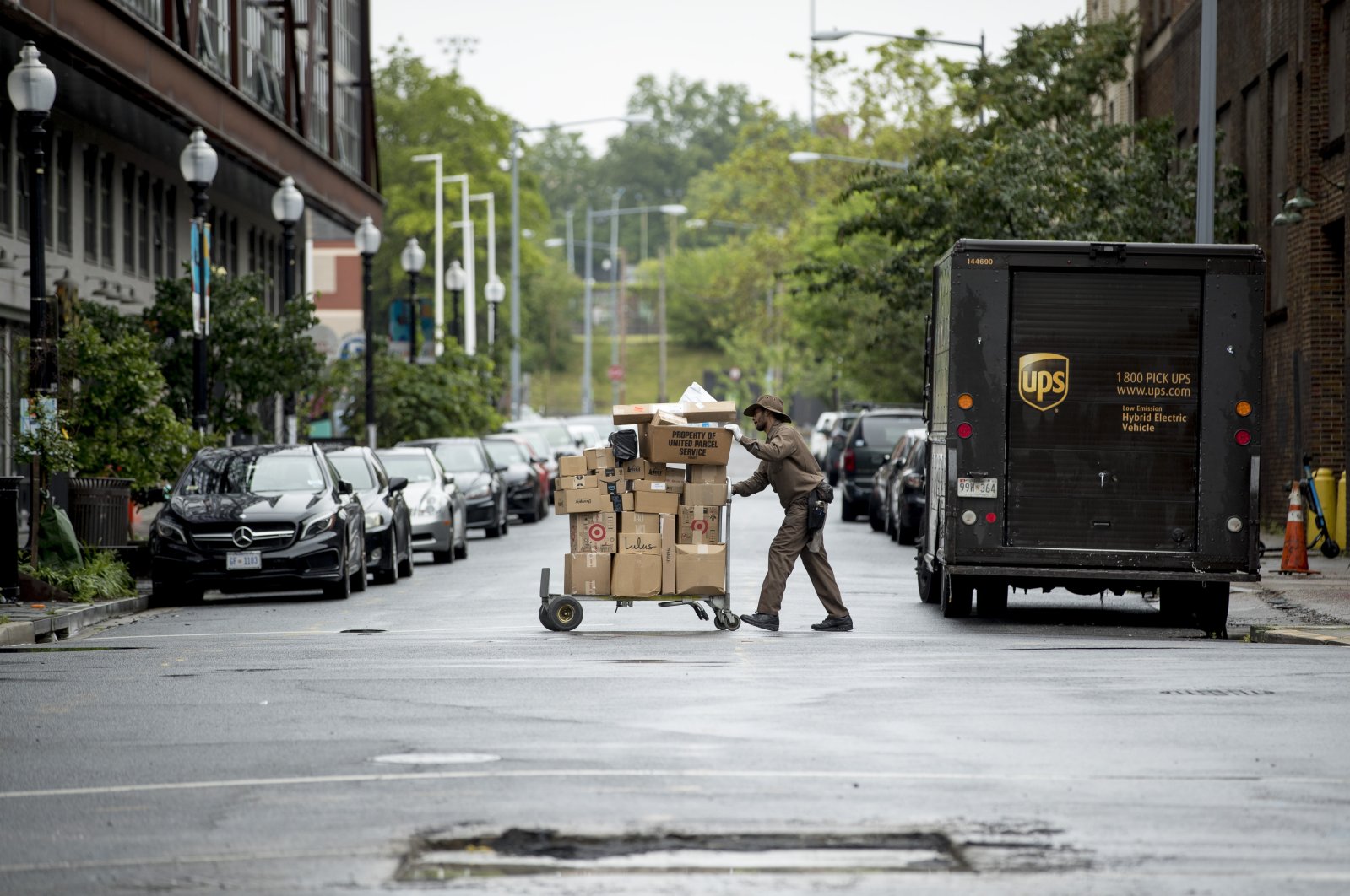 A delivery man pushes a cart full of packages to deliver to an apartment building on an almost empty street in the Shaw neighborhood of Washington, D.C., U.S., May 22, 2020. (AP Photo)
