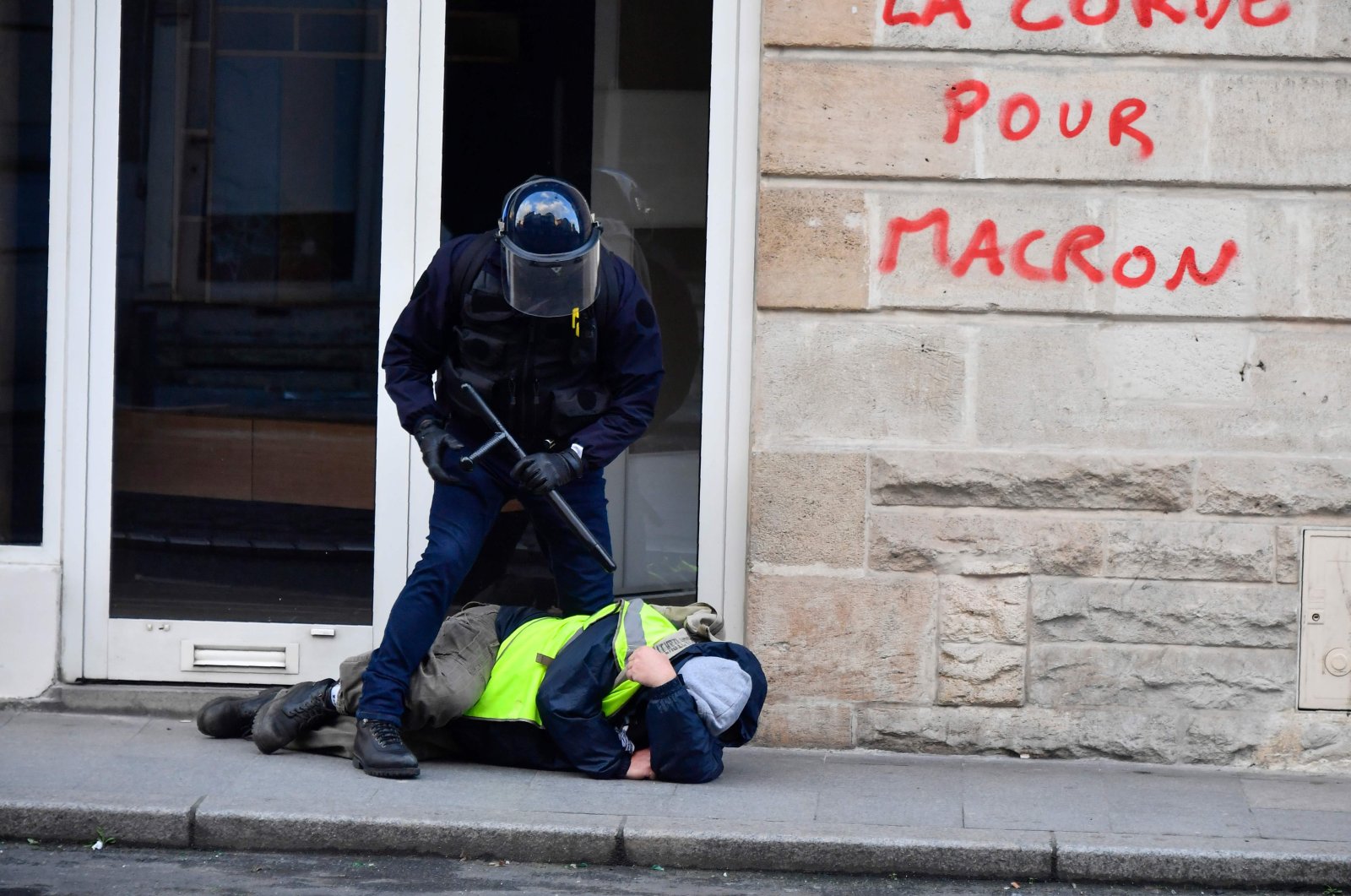 A riot policeman stands over a protestor wearing a yellow vest during clashes with protesters in a demonstration called by the "Yellow Vests" movement in Bordeaux, Feb. 2, 2019. (AFP Photo)
