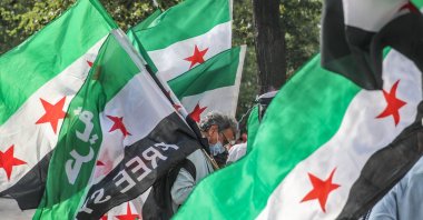 A Syrian activist carries the Syrian Revolution flag during a rally for the anniversary of 2013 Chemical Attack on Ghota, at Fontaine des Innocents in the Les Halles district in the 1st arrondissement of Paris, France. 21 August 2020. (EPA Photo)