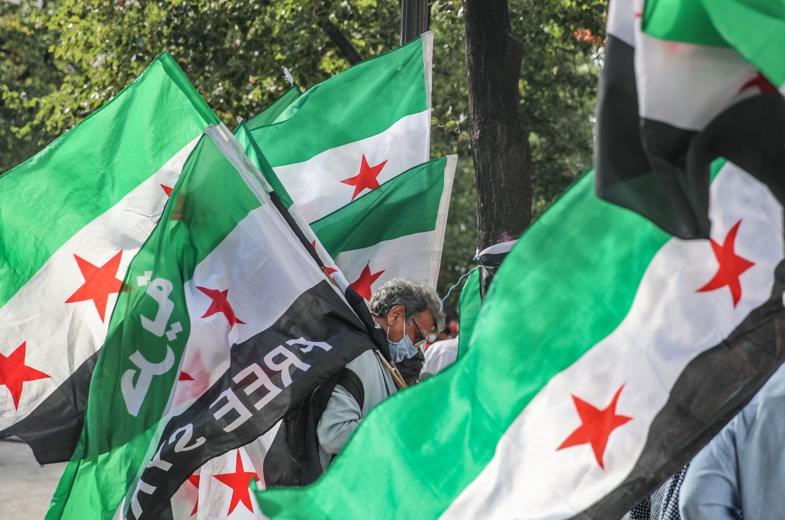 A Syrian activist carries the Syrian Revolution flag during a rally for the anniversary of 2013 Chemical Attack on Ghota, at Fontaine des Innocents in the Les Halles district in the 1st arrondissement of Paris, France. 21 August 2020. (EPA Photo)
