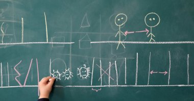 A student draws shapes that resemble the microscopic view of the coronavirus disease on a classroom board at Al-Mahdi School in Tehran, Iran, Sept. 5, 2020. (West Asia News Agency via Reuters)