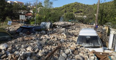Vehicles are covered with rocks following a storm in the village of Assos, on the Ionian island of Kefalonia, western Greece, Sept. 20, 2020. (AP Photo)