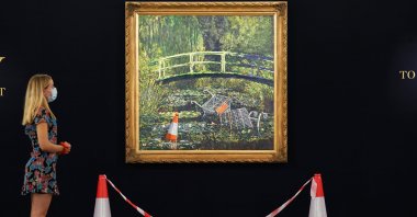 A visitor stands in front of a painting by the artist Banksy, titled "Show me the Monet," at Sotheby's in London, Britain, Sept. 18, 2020. (Sotheby's handout via Reuters)