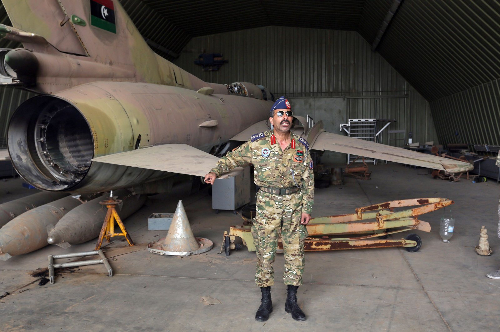 Group Captain Muhammad Qanunu, the military spokesperson of the U.N.-recognized Government of National Accord (GNA) forces, stands by a partially disassembled MiG 23 aircraft, after seizing al-Watiya air base from Haftar on May 18, 2020. (AFP Photo)