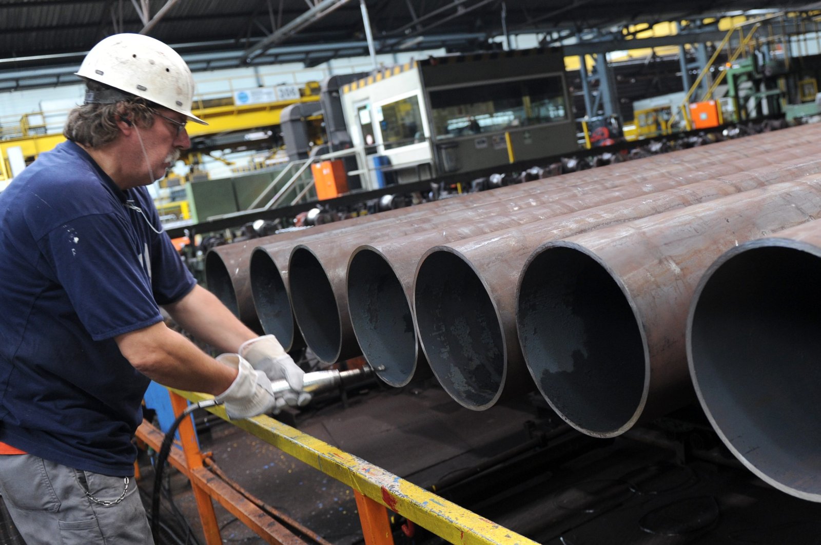 An employee checks a steel pipe in the manufacturing hall at Vallourec and Mannesmann in Dusseldorf, Germany, July 9, 2013. (AP Photo)