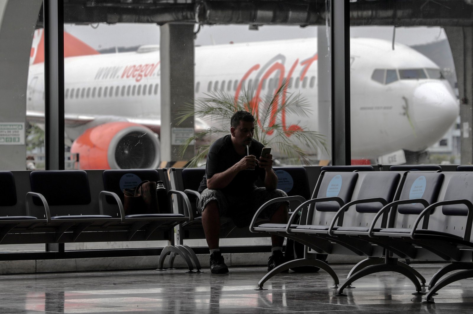 A man checks his phone in a waiting room at Santos Dumont airport, in Rio de Janeiro, Brazil, Aug. 20, 2020. (EPA Photo)