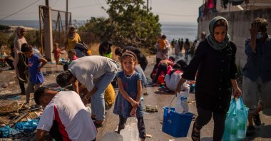 A girl waits to fill bottles with water near a temporary migrant camp on the Greek Aegean island of Lesbos, Sept. 16, 2020. (AFP Photo)