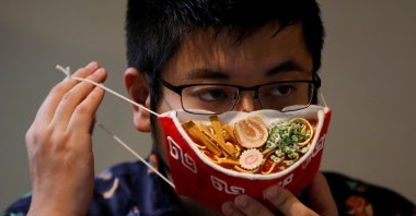 Japanese designer Takahiro Shibata's puts on his protective mask that looks like a steaming bowl of ramen noodle soup at his house, following the coronavirus disease (COVID-19) outbreak in Yokohama, Japan on Sept. 23, 2020. (Reuters Photo)