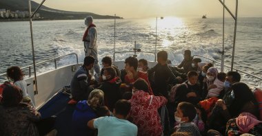 Migrants sit on a Turkish Coast Guard vessel after they were pulled off life rafts, during a rescue operation in the Aegean Sea, between Turkey and Greece, Sept. 12, 2020. (AP Photo)