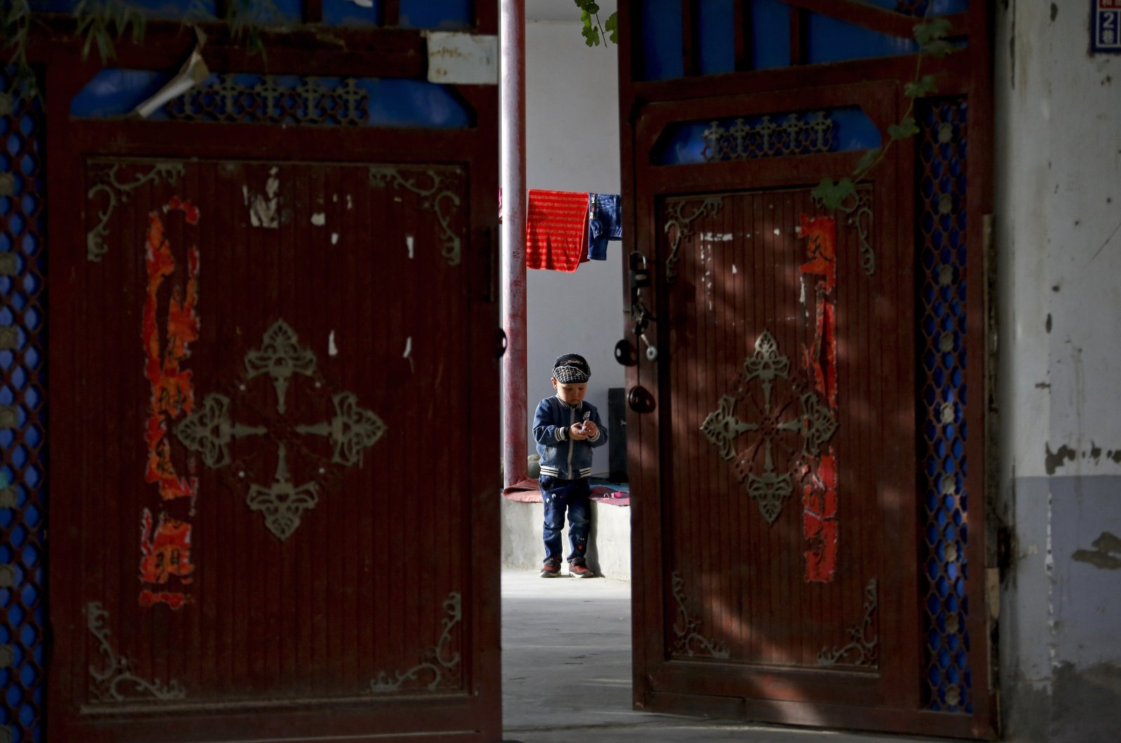 An Uighur child plays alone in the courtyard of a home at the Unity New Village in Hotan, in western China's Xinjiang region, Sept. 20, 2018. (AP Photo)
