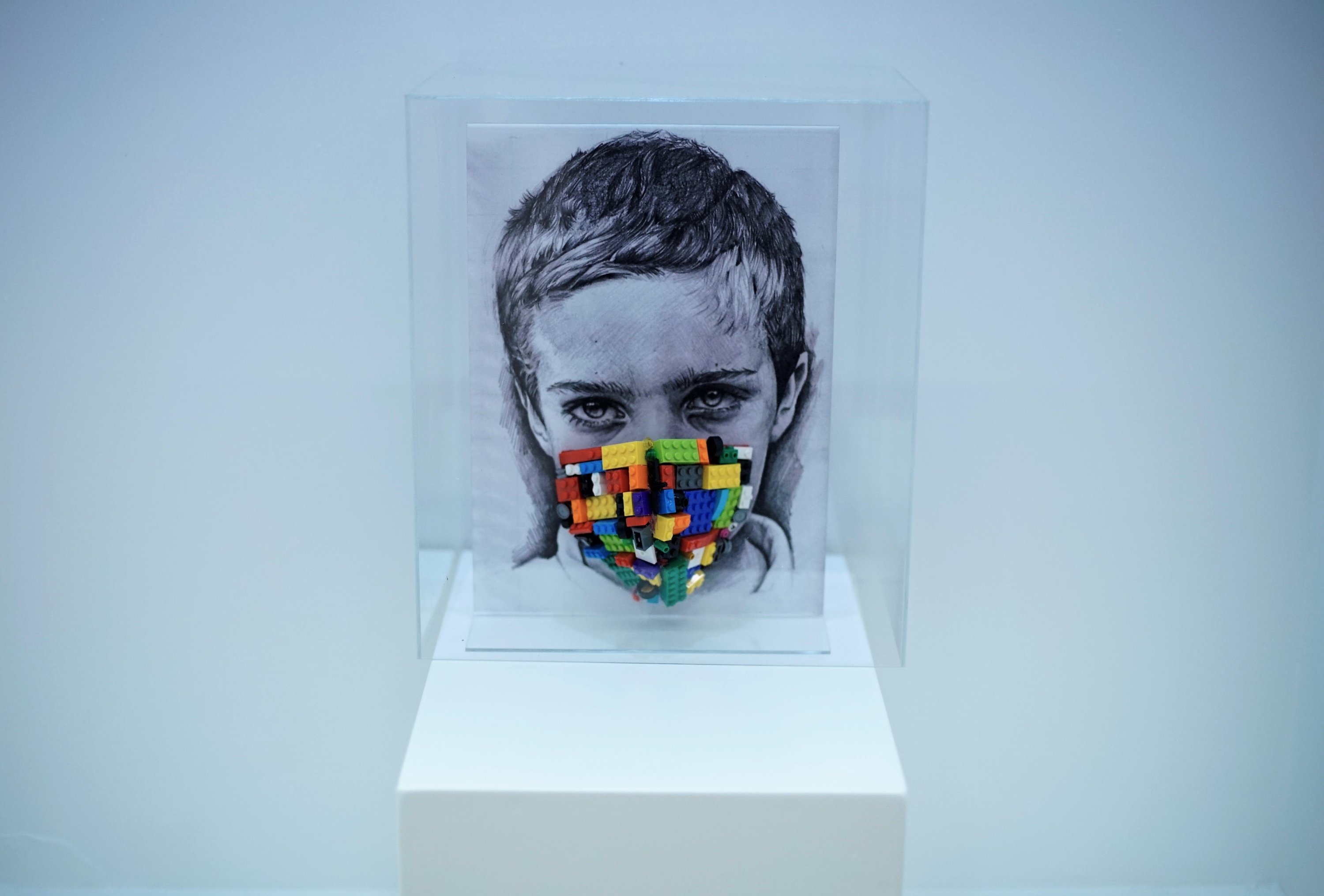Simay Bülbül, “Childhood in the Glass Lantern,” installation of Lego pieces, plexi, masks on textiles, 33 by 24 centimeters.
