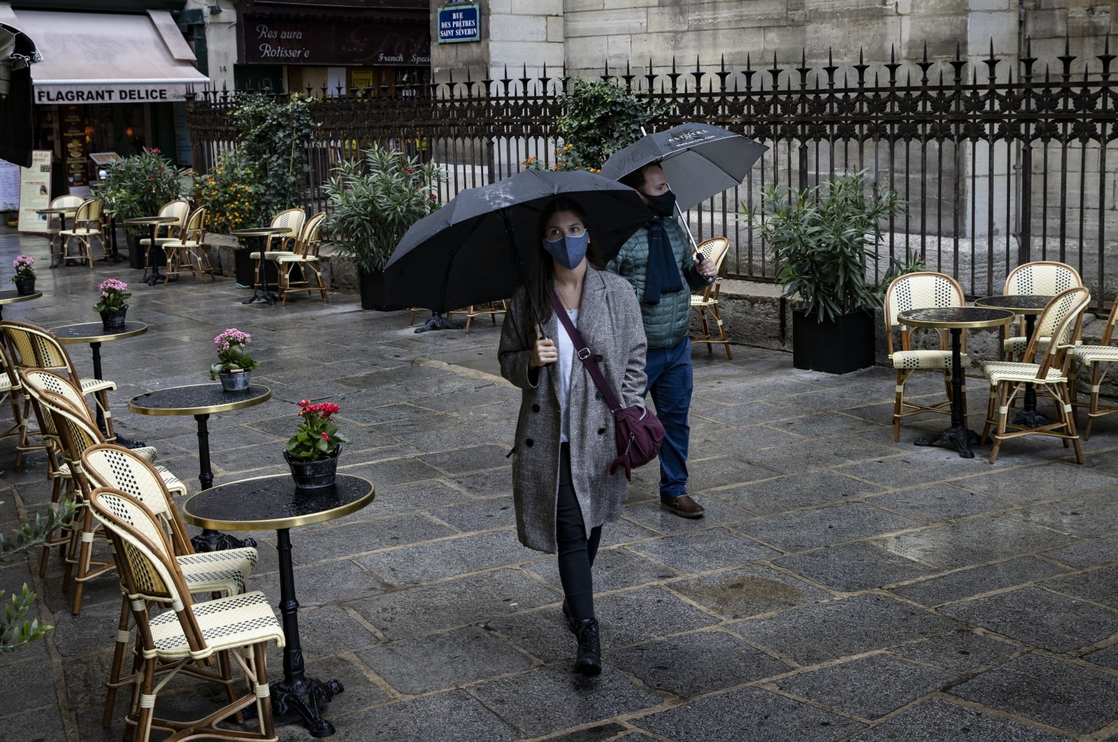 A couple of pedestrians wearing protective face masks walk past a deserted bistrot terrace, Paris, Sept. 25, 2020. (EPA Photo)
