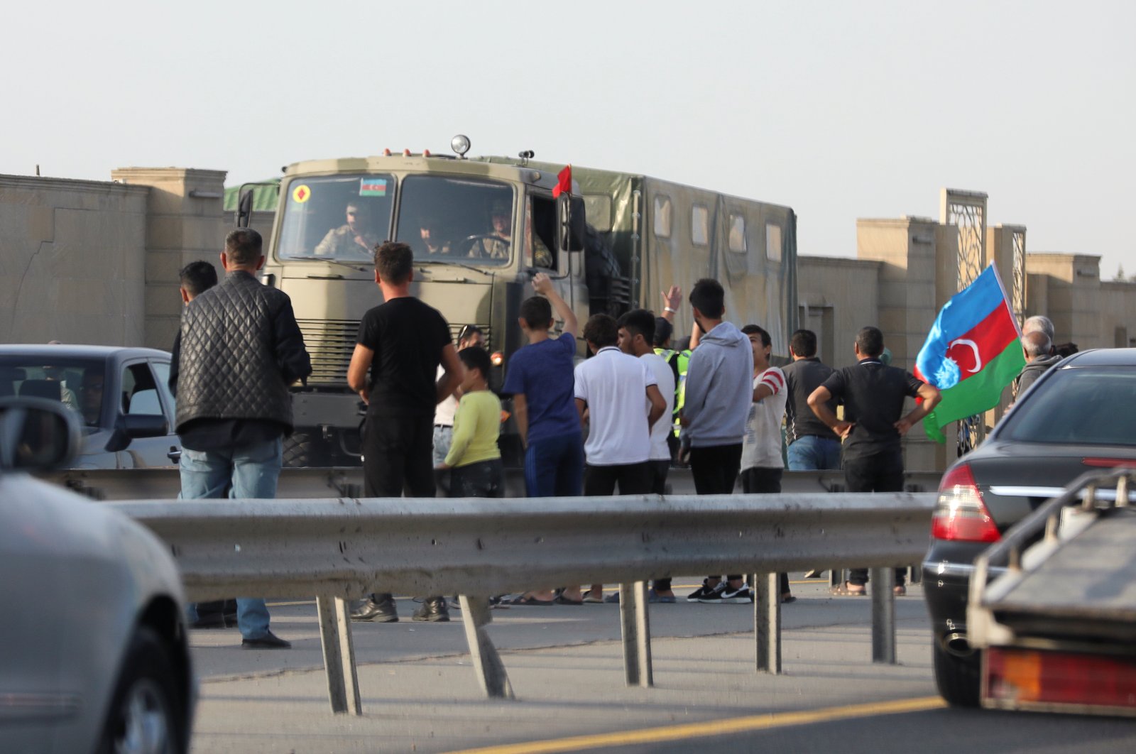 People line up along the roadside to greet Azerbaijani service members, who drive a truck in Baku, Azerbaijan Sept. 27, 2020. REUTERS