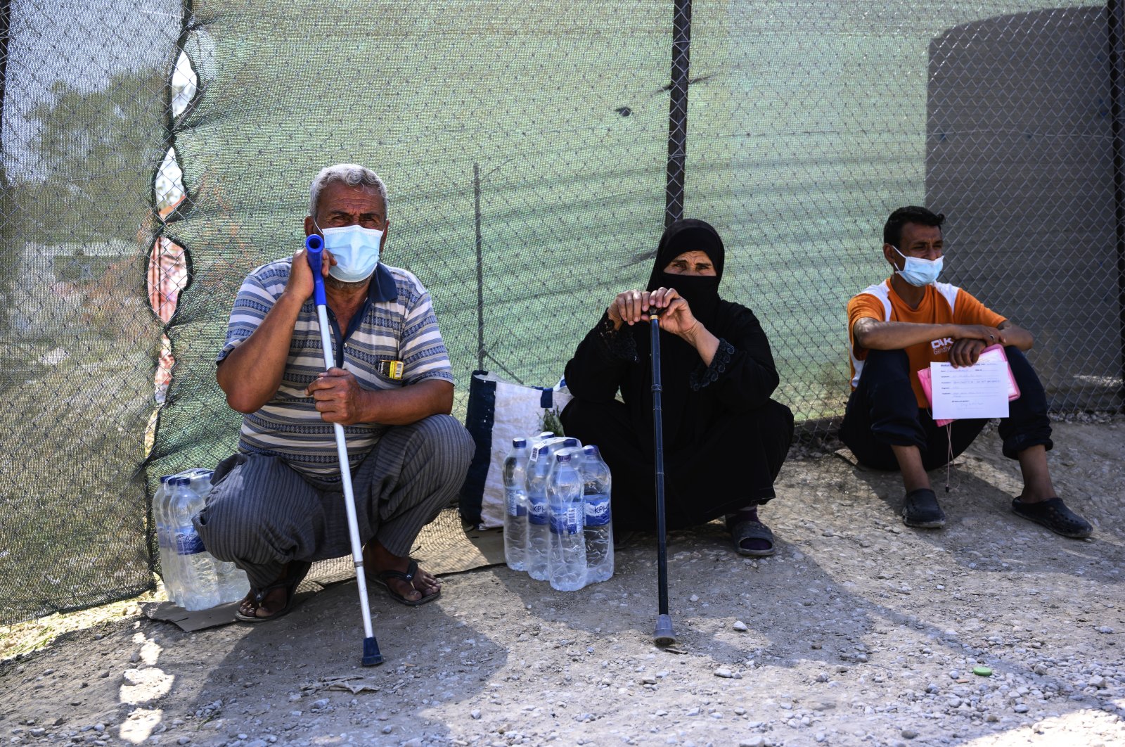 Migrants sit outside the perimeter of the Moria refugee camp on the northeastern Aegean island of Lesbos, Greece, Sept. 2, 2020. (AP Photo/Vangelis Papantonis)