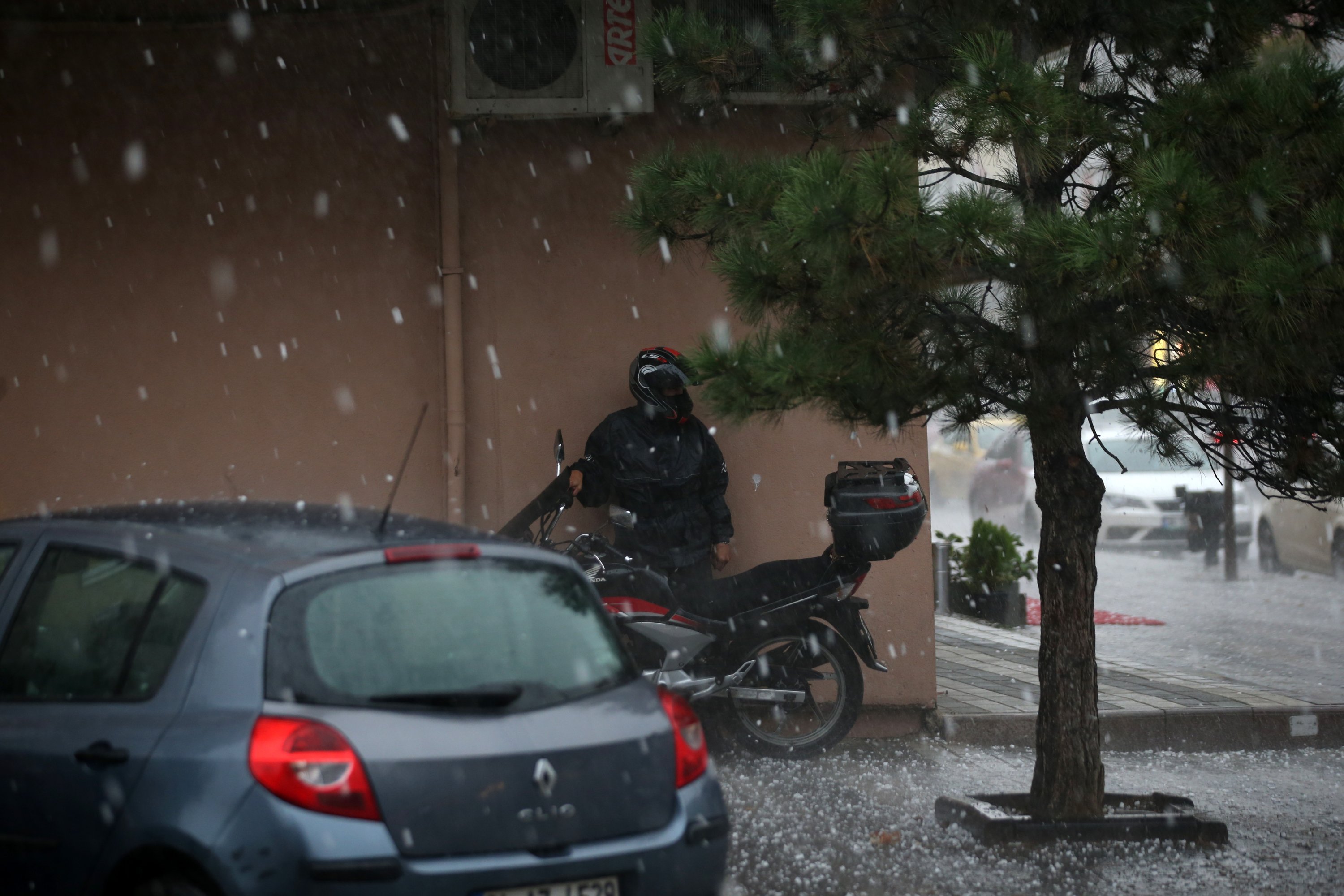  Një shofer motoçikletash qëndron pranë një ndërtese apartamenti për të mbrojtur veten nga breshëri, në rrethin Üsküdar të Stambollit, Turqi, 29 shtator, 2020. (AA Photo)