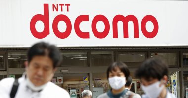 Passers-by walk past a NTT DoCoMo shop in Tokyo, Sept. 29, 2020. (AP Photo)