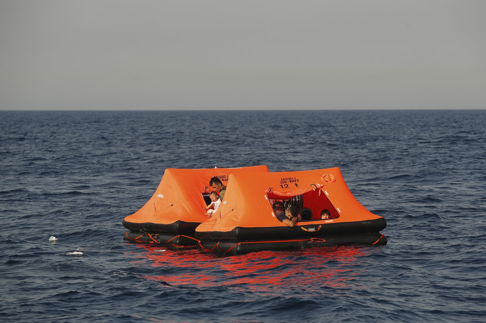 Afghan migrants watch from inside a life raft during a rescue operation by the Turkish coast guard, in the Aegean Sea, between Turkey and Greece, Saturday, Sept. 12, 2020. (AP Photo)