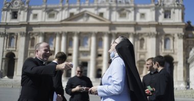 A priest and a nun laugh as they wait for Pope Francis to recite the Angelus noon prayer, in St. Peter's Square at the Vatican, Sept. 6, 2020. (AP Photo)