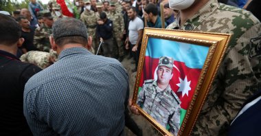 A servicemen holds a portrait of Colonel Lieutenant Makhman Ganbarov, who was killed during the fighting in Armenia-occupied Nagorno-Karabakh region, during a funeral in the city of Barda, Azerbaijan Oct. 1, 2020. (Reuters Photo)