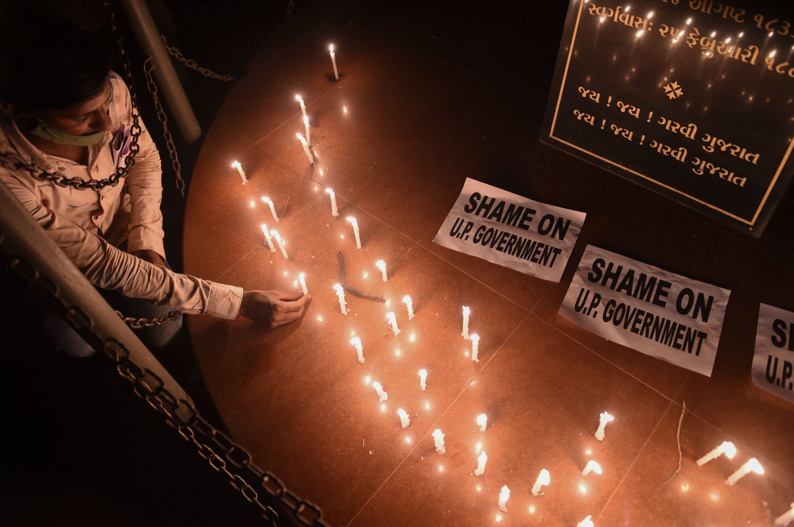 A member of the National Students' Union of India (NSUI) places a candle beside placards after a candlelight vigil following accusations of Indian police forcibly cremating the body of a 19-year-old female victim who was allegedly gang-raped by four men in the Bool Garhi village of Uttar Pradesh state, in Ahmedabad, India, Sept. 30, 2020. (AFP Photo)