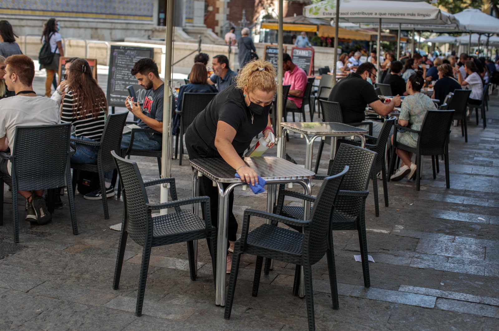 A waitress disinfects a table at a bar terrace in Valencia, Spain, Sept. 29, 2020. (EPA Photo)