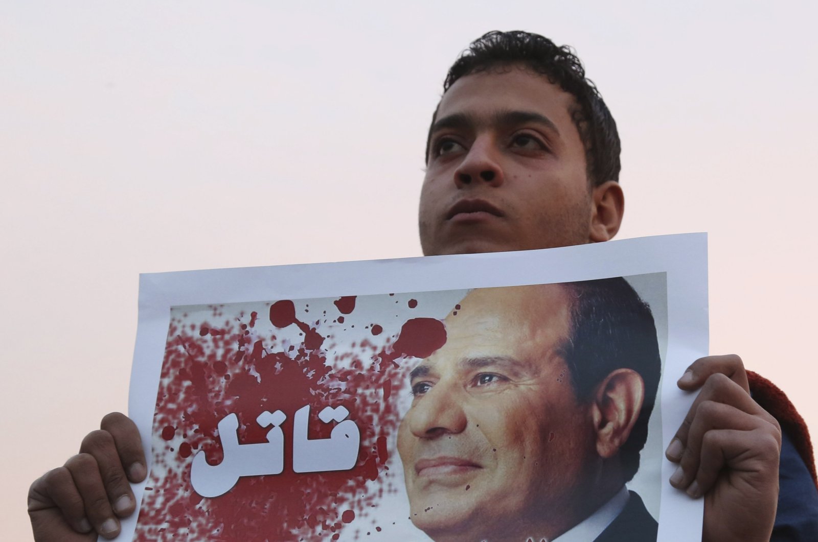A man holds a poster of Egyptian President Abdel-Fattah el-Sissi with the word "Killer" on it during a silent protest over a bridge in Cairo, Feb. 14, 2015. (Reuters Photo)