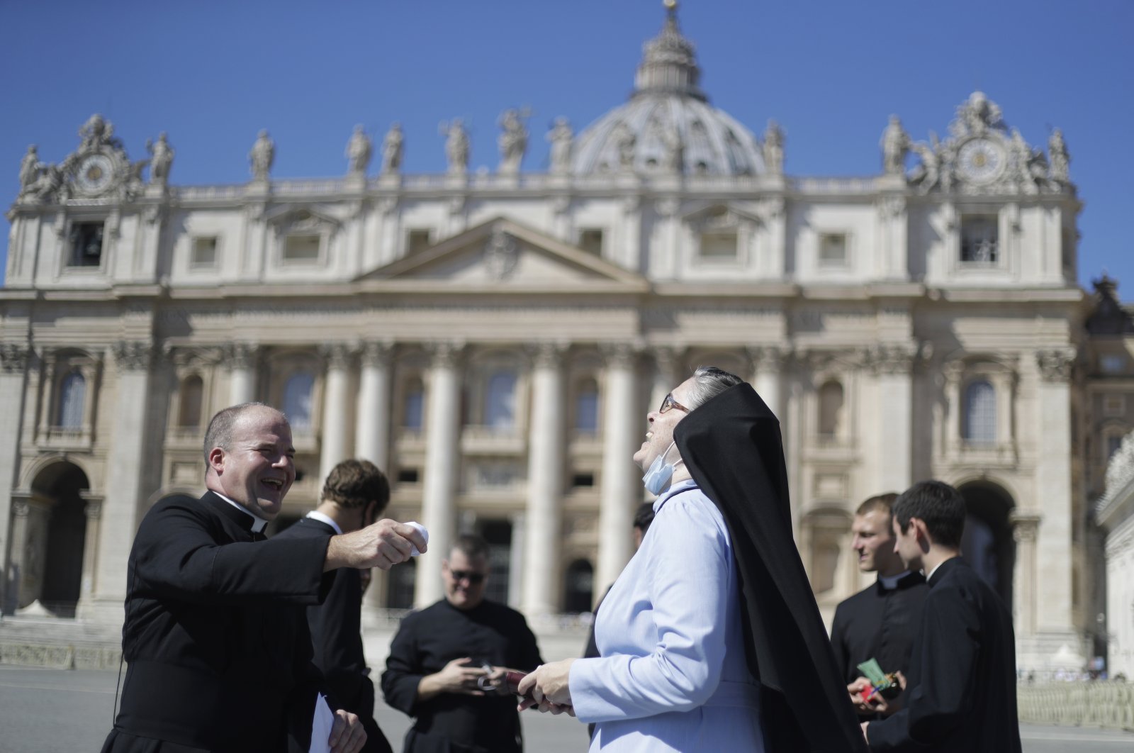 A priest and a nun laugh as they wait for Pope Francis to recite the Angelus noon prayer, in St. Peter's Square at the Vatican, Sept. 6, 2020. (AP Photo)